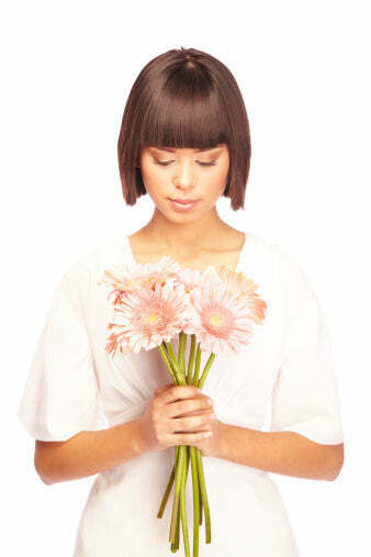 woman with pixie hairstyle holding pink flowers and looking down